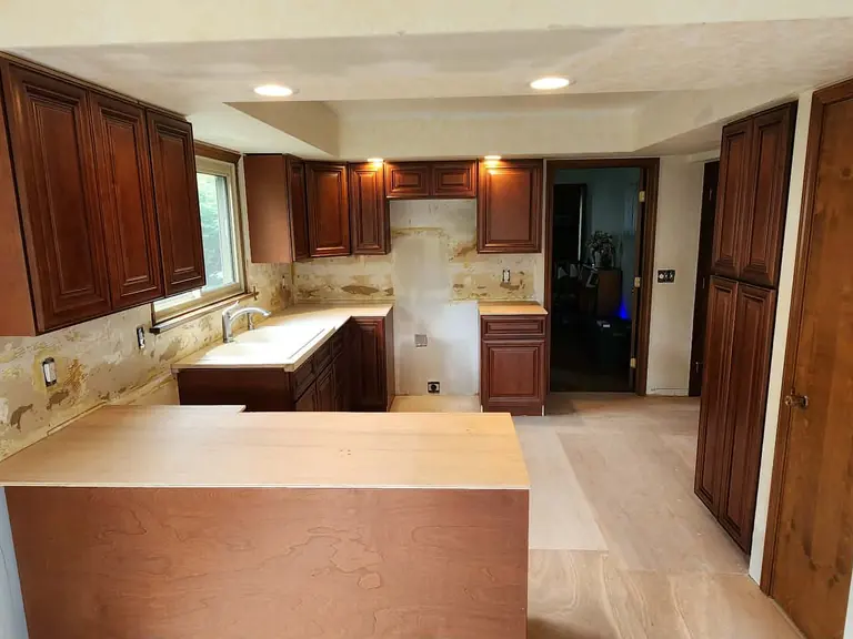 Cherry kitchen mid-remodel — cabinets set, temporary counters, stripped walls