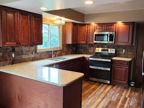 Finished cherry kitchen with quartz counters and stone backsplash by R&R